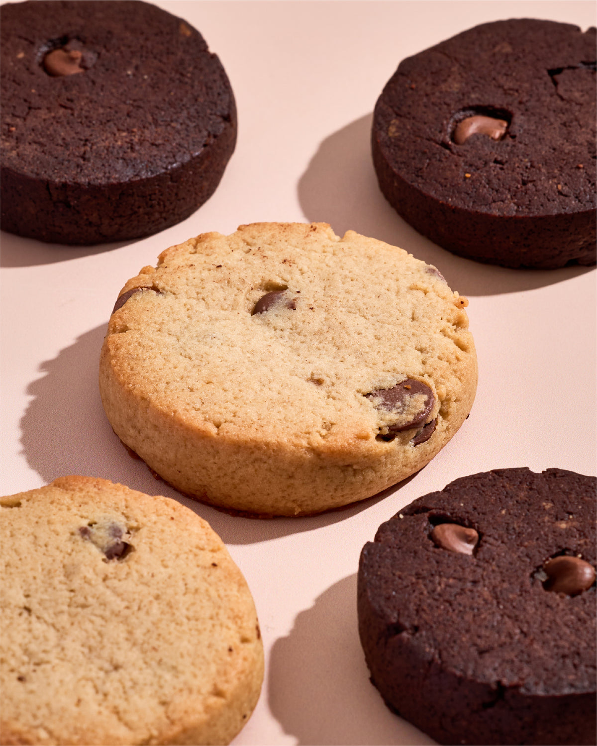 Primal Bakery Prookies in Chocolate Chip and Double Chocolate flavors arranged on a pink background