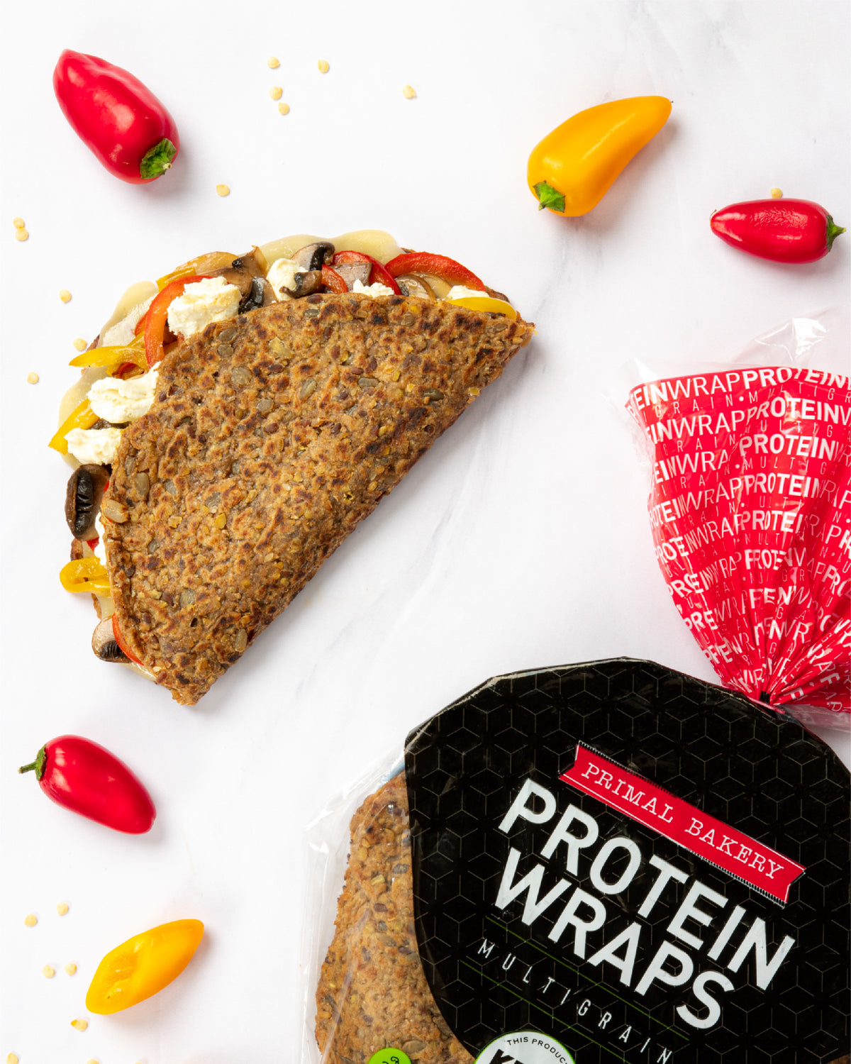 Primal Bakery Multigrain Protein Wraps package next to a filled wrap with sautéed peppers, mushrooms, and cheese.